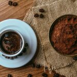 Taza de café con granos tostados y café molido sobre una mesa de madera